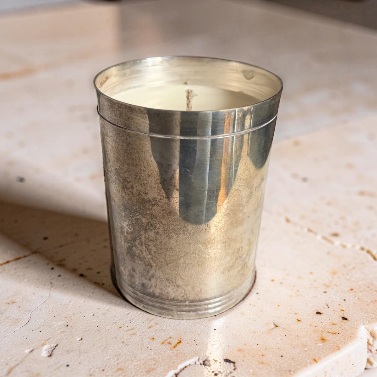 Silver candle holder with a candle inside on a textured surface