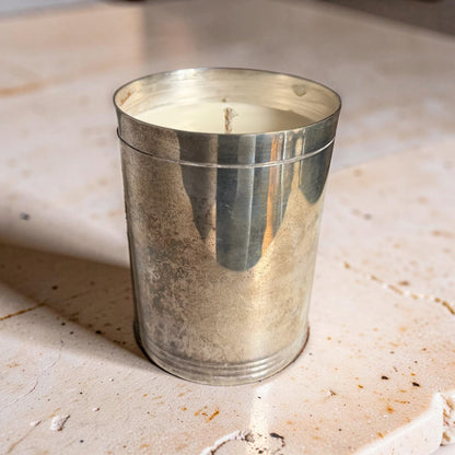 Silver candle holder with a candle inside on a textured surface