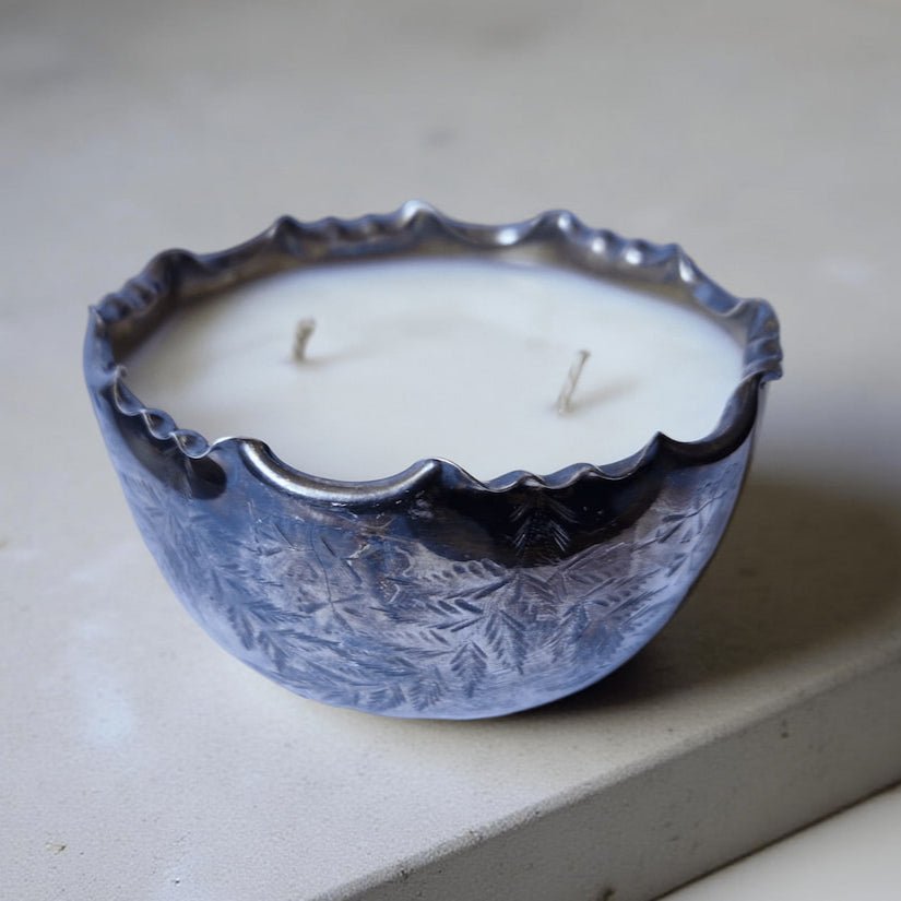 metal candle holder with a white candle on a light gray surface