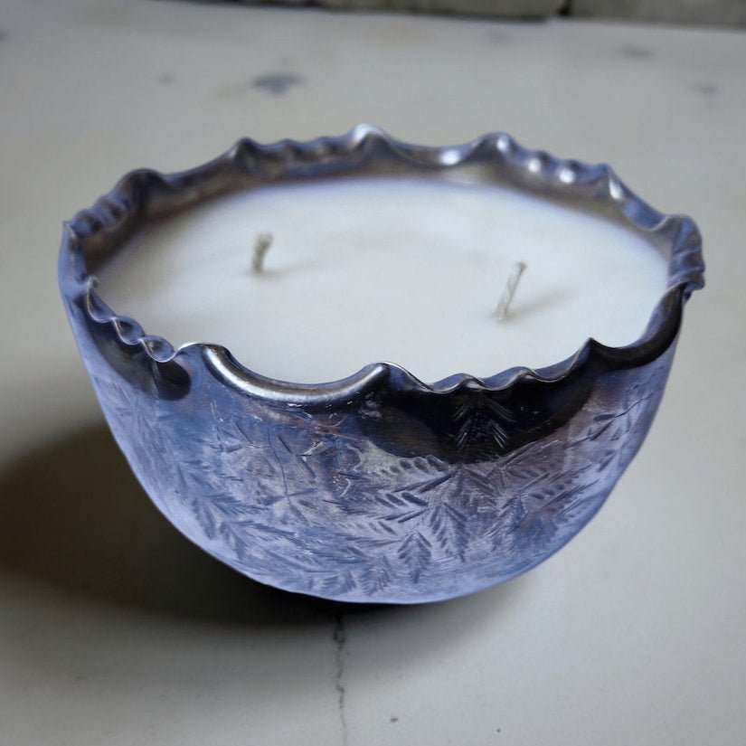 Candle in a decorative metal holder on a plain surface