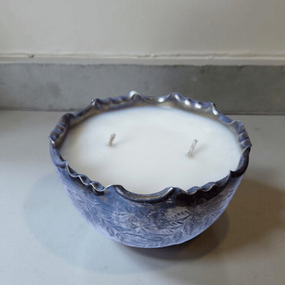 Decorative candle in a blue ceramic holder on a plain surface