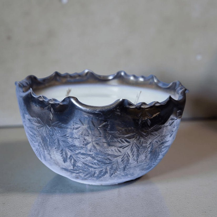 Decorative candle in a textured metal holder on a plain background