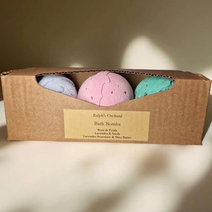 Three bath bombs in a cardboard box with a label on a beige background