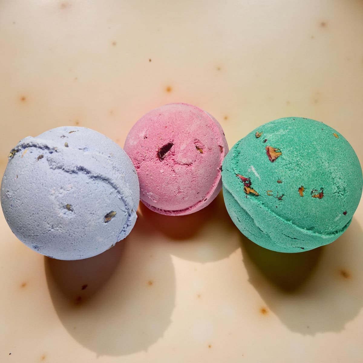 Three colorful bath bombs on a light surface