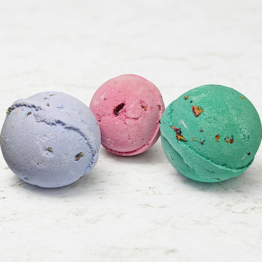 Three colorful bath bombs on a light surface