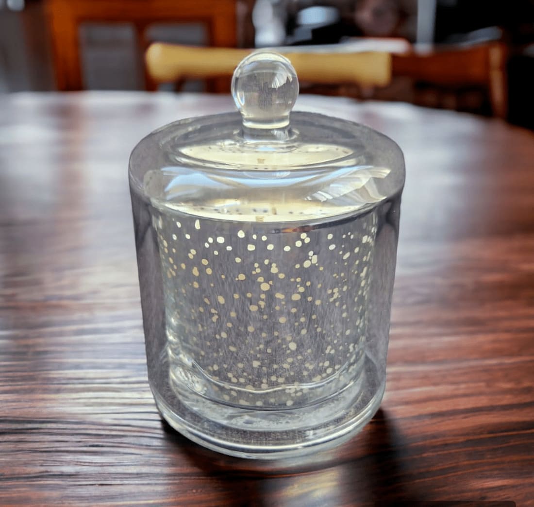 Clear glass candle holder with decorative dots on a wooden table