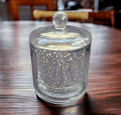 Clear glass candle holder with decorative dots on a wooden table