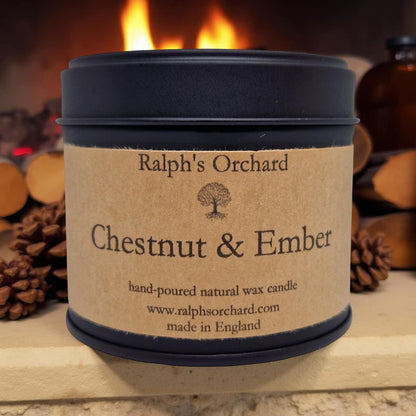 Candle labeled 'Ralph's Orchard Chestnut & Ember' with a fireplace and logs in the background