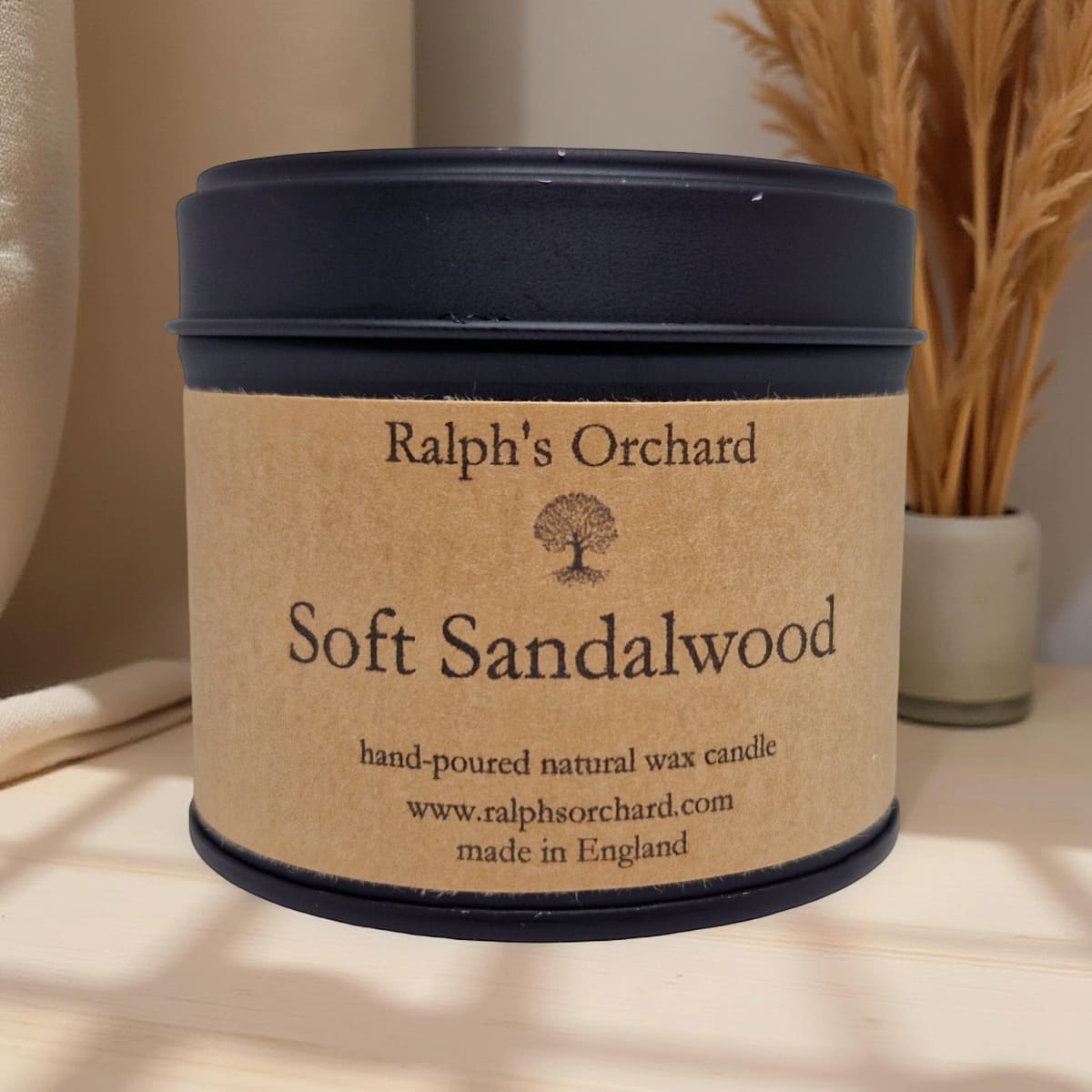 Candle labeled 'Ralph's Orchard Soft Sandalwood' on a neutral background