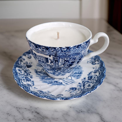 Blue and white teacup candle on a matching saucer on a marble surface