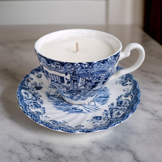 Blue and white teacup candle on a matching saucer on a marble surface