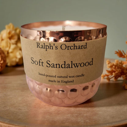 Candle with 'Ralph's Orchard Soft Sandalwood' label on a wooden surface