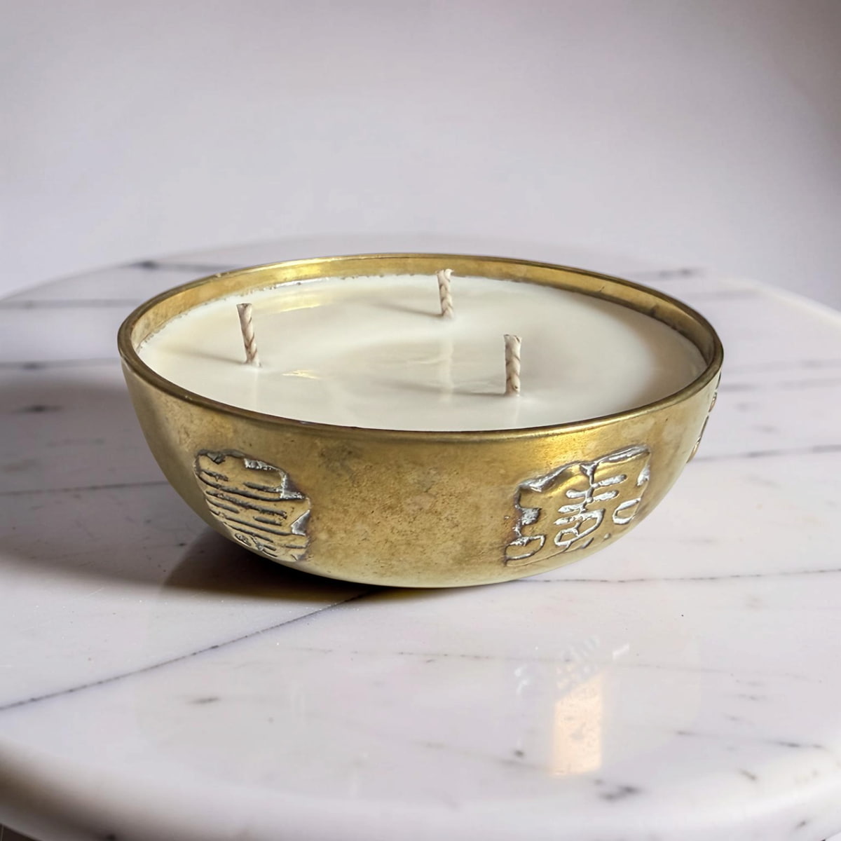 Decorative candle in a gold holder on a marble surface