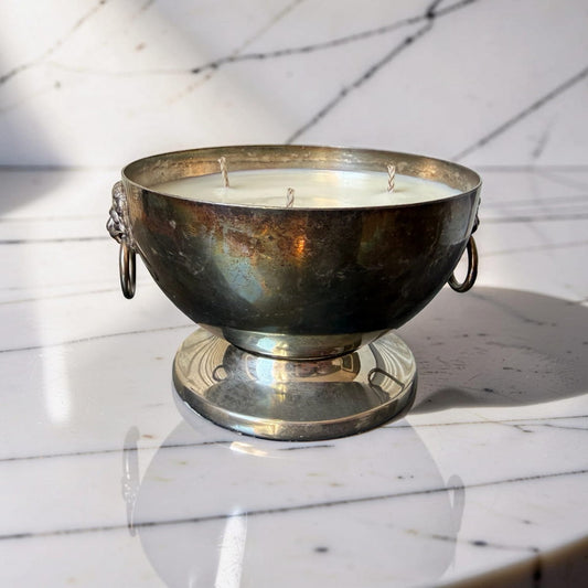 Decorative candle in a metal bowl on a marble surface