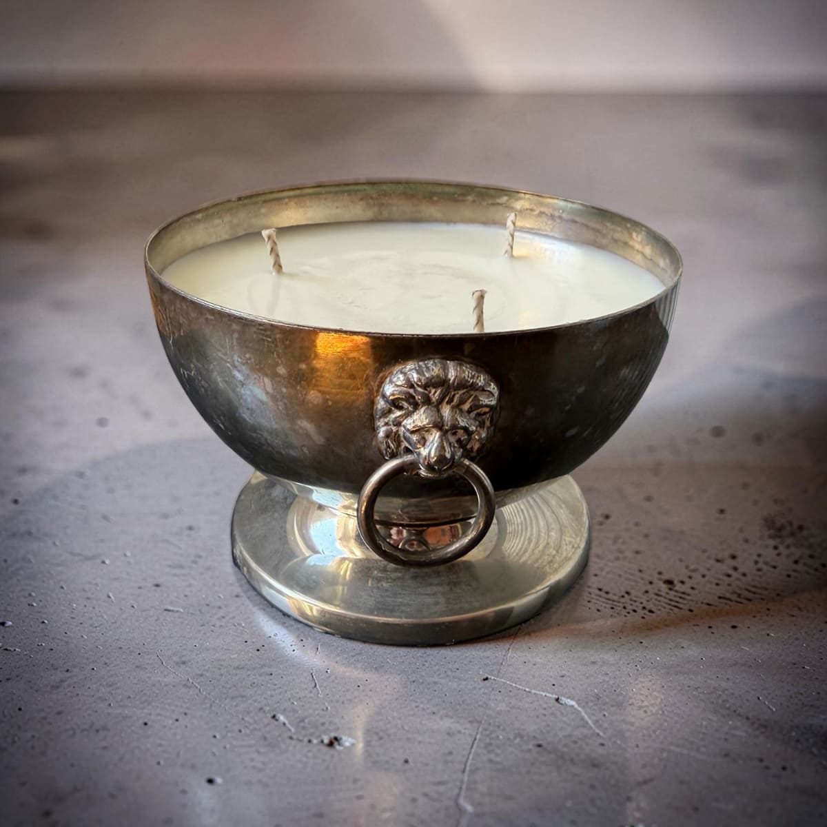 Decorative candle in a metal holder with lion head design on a metallic surface