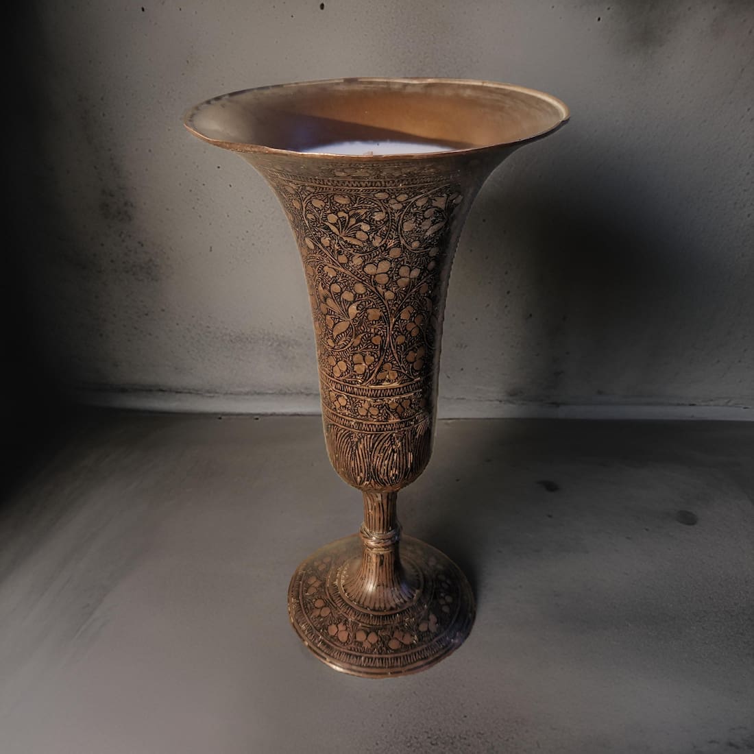 Decorative bronze vase with intricate patterns on a plain background