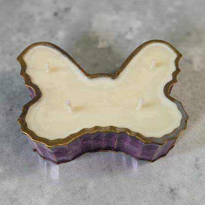 Candle with a butterfly design on a gray surface