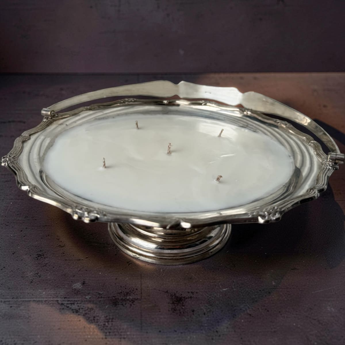 Silver platter with a candle inside on a dark surface