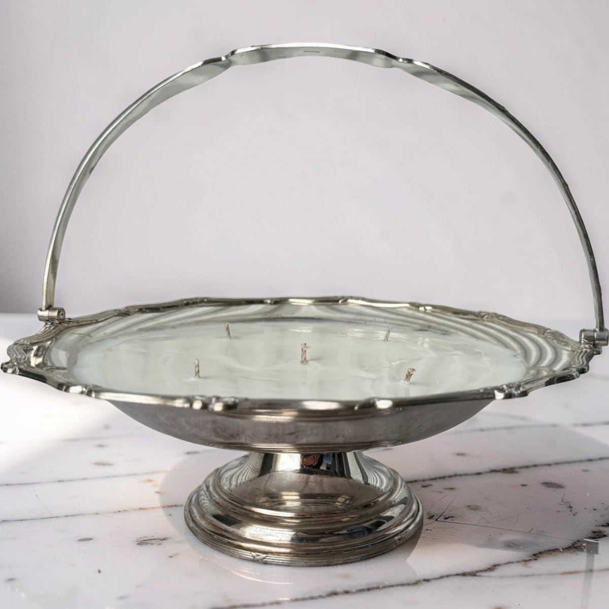 Silver metal basket with a handle on a marble surface