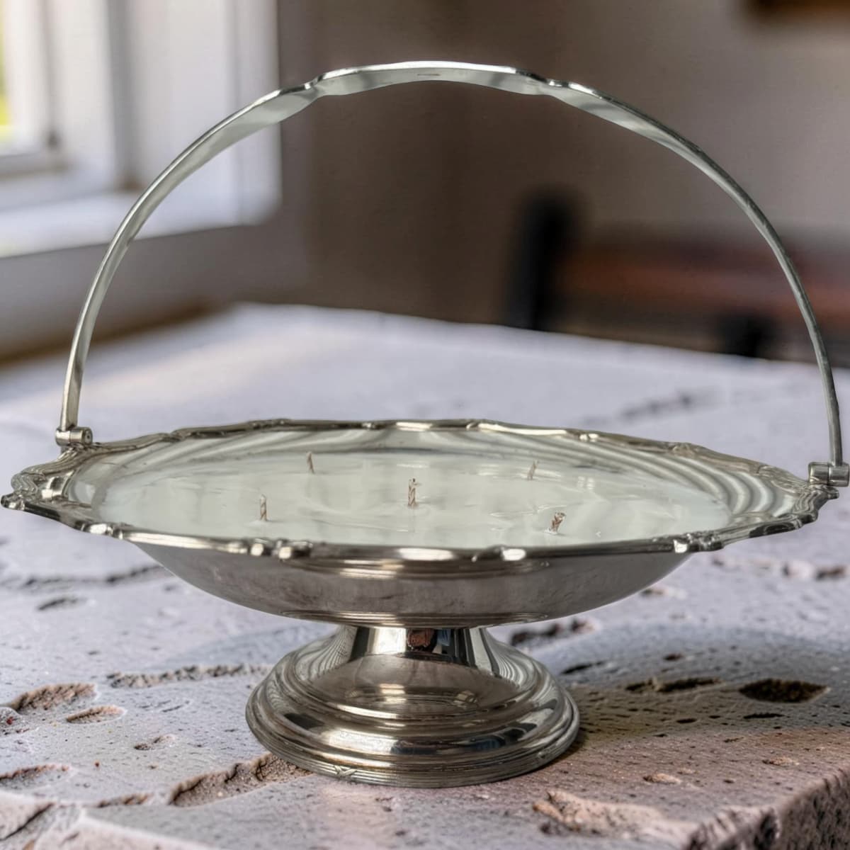 Silver cake stand with a handle on a marble surface