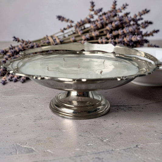 Silver cake stand on a textured surface with lavender in the background