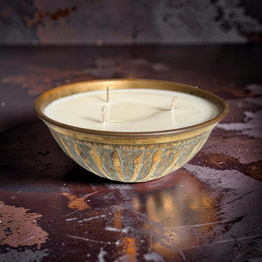 Decorative candle in a metal bowl on a textured surface
