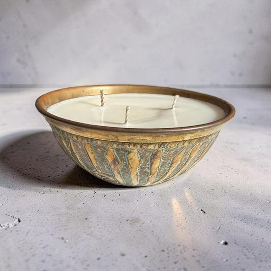 Candle in a decorative ceramic bowl on a concrete surface