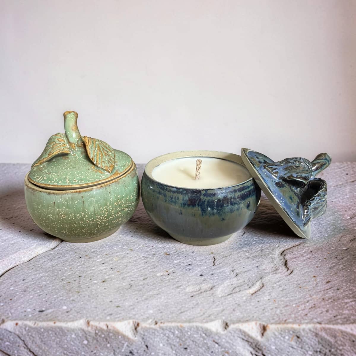 Three ceramic containers with lids on a textured surface