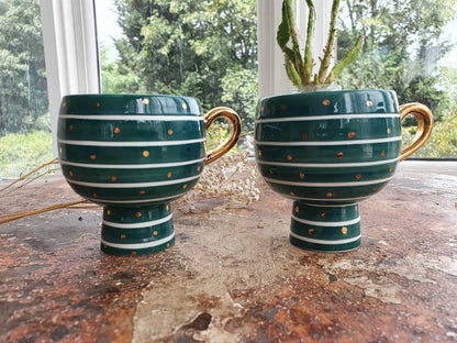 Two green ceramic planters with gold stripes on a wooden surface.