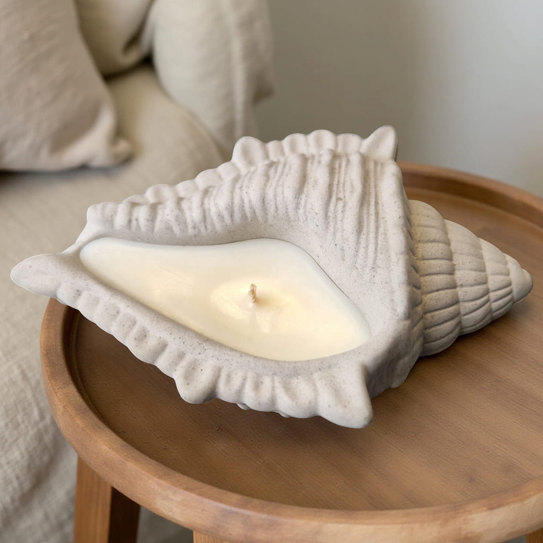 Shell-shaped candle on a wooden surface with a neutral background