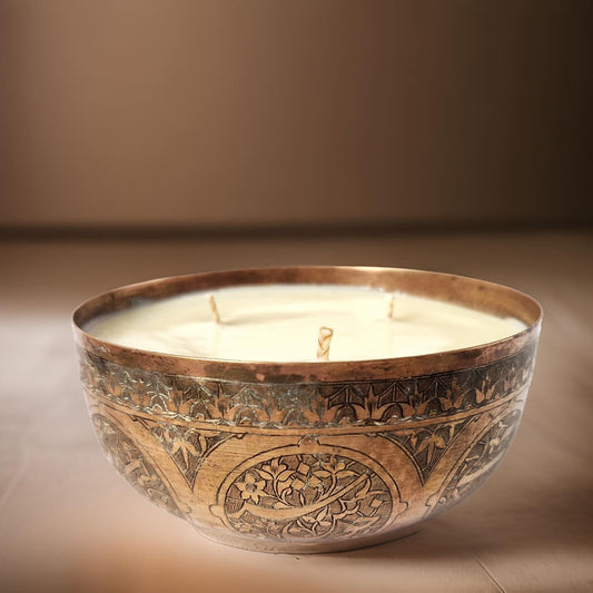 Decorative candle in an ornate bronze holder on a brown background