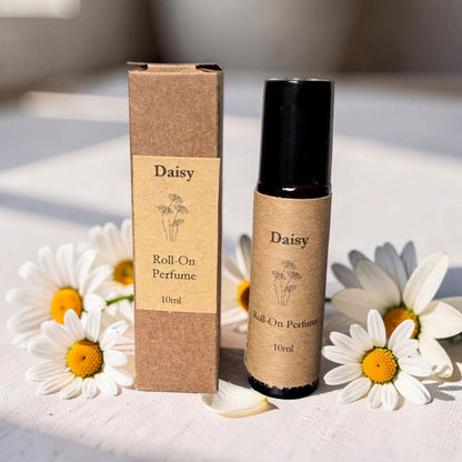 Daisy roll-on perfume with packaging on a white surface with daisies.