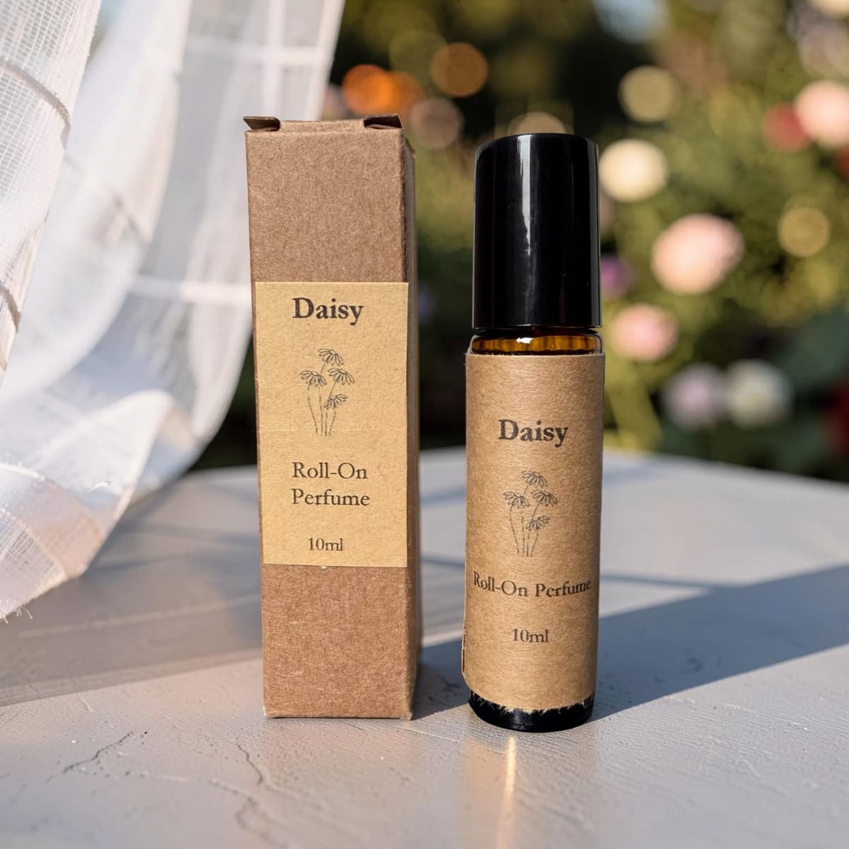 Daisy roll-on perfume bottle and packaging on a light surface with blurred greenery in the background
