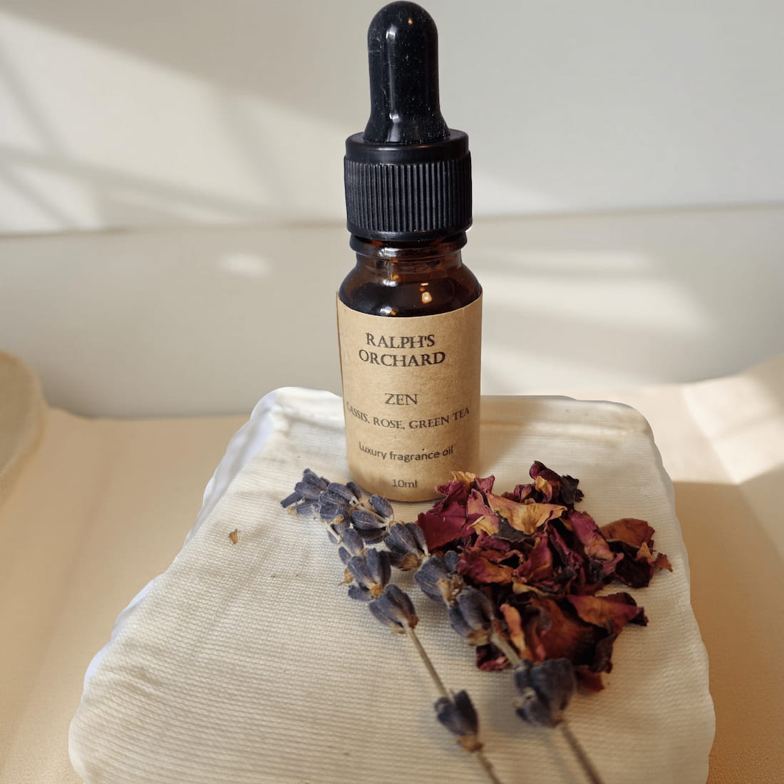 Bottle of Ralph's Orchard Zen fragrance oil with dried flowers on a textured surface