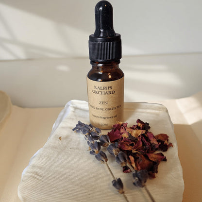 Bottle of Ralph's Orchard Zen fragrance oil with dried flowers on a textured surface