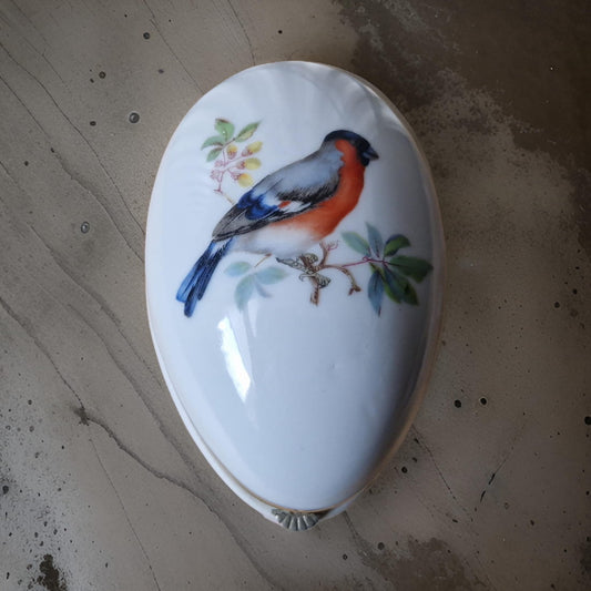 Decorative spoon with a painted bird design on a speckled surface