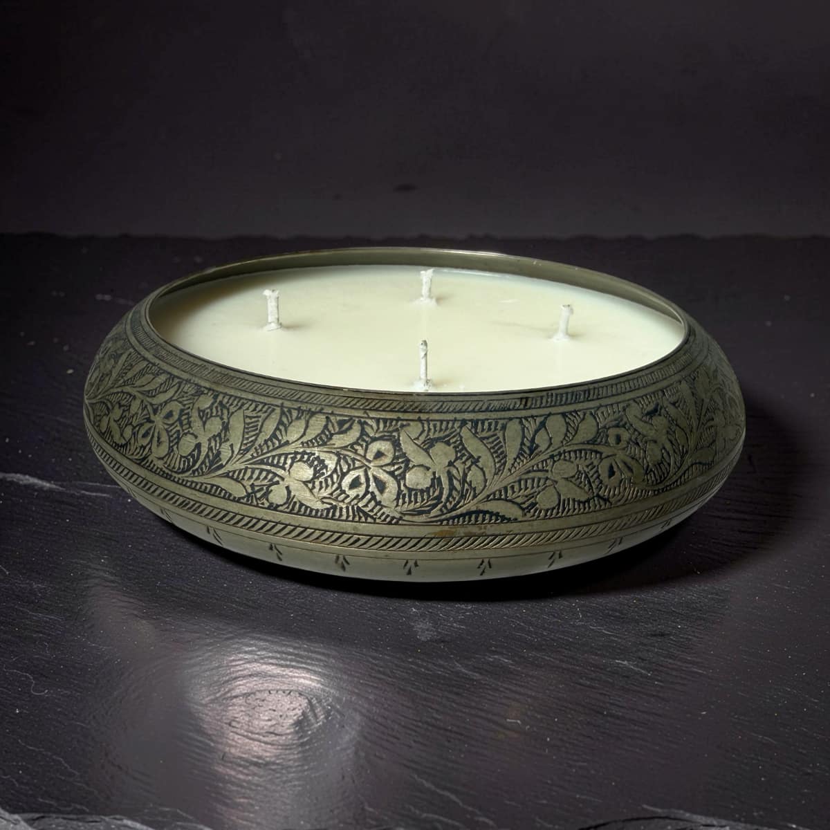 Decorative candle in an ornate holder on a dark surface