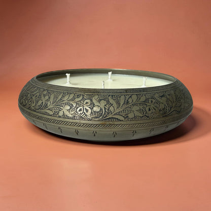 Decorative candle in a round, embossed container on a peach background