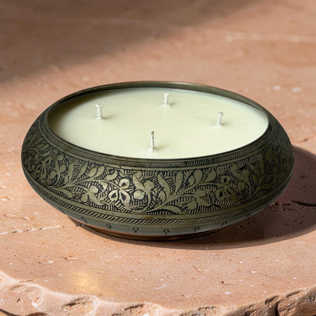 Decorative candle in a patterned holder on a stone surface