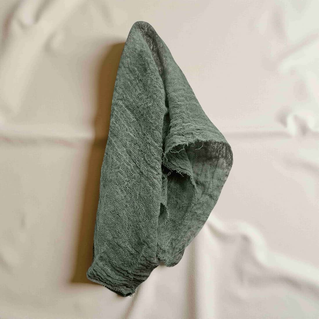 Green fabric hanging on a white towel rack