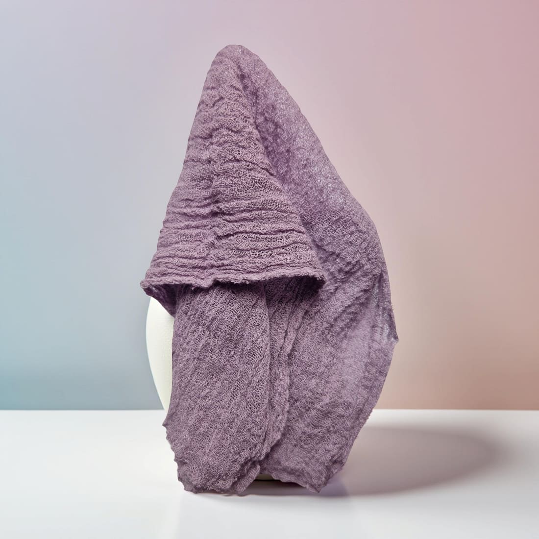 Folded purple towel on a white surface with a gradient background