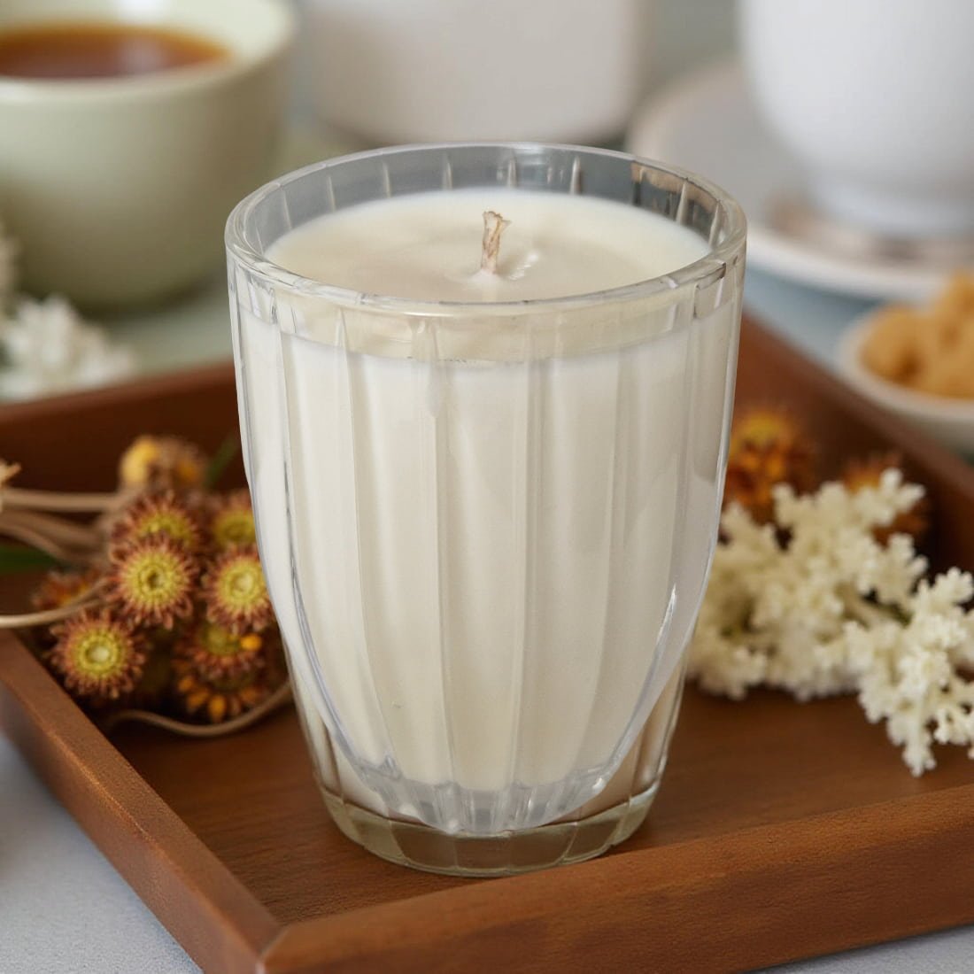 Glass candle on a wooden tray with decorative elements