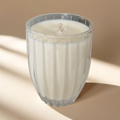 White candle in a glass container on a beige background