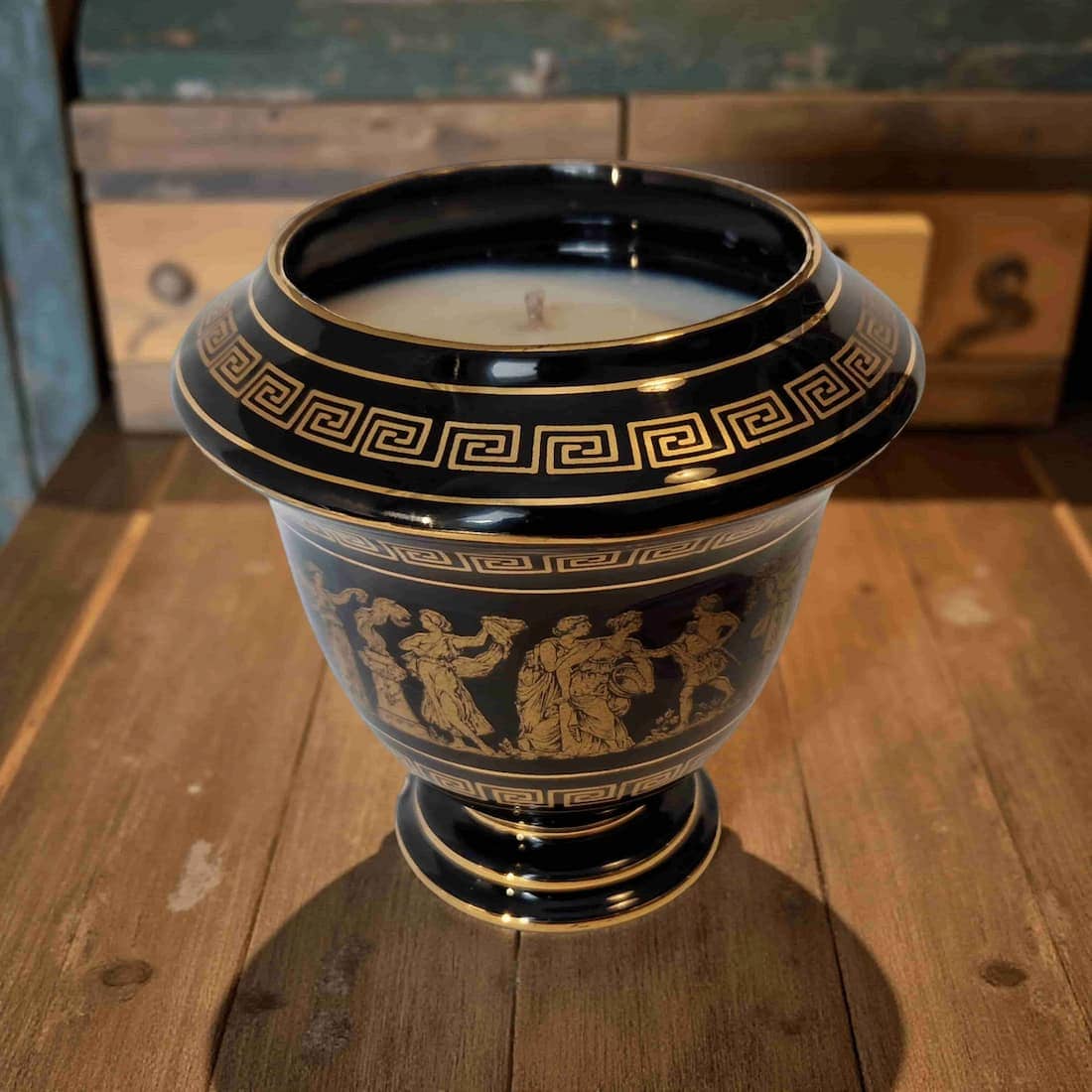 Decorative black urn with gold detailing on a wooden surface