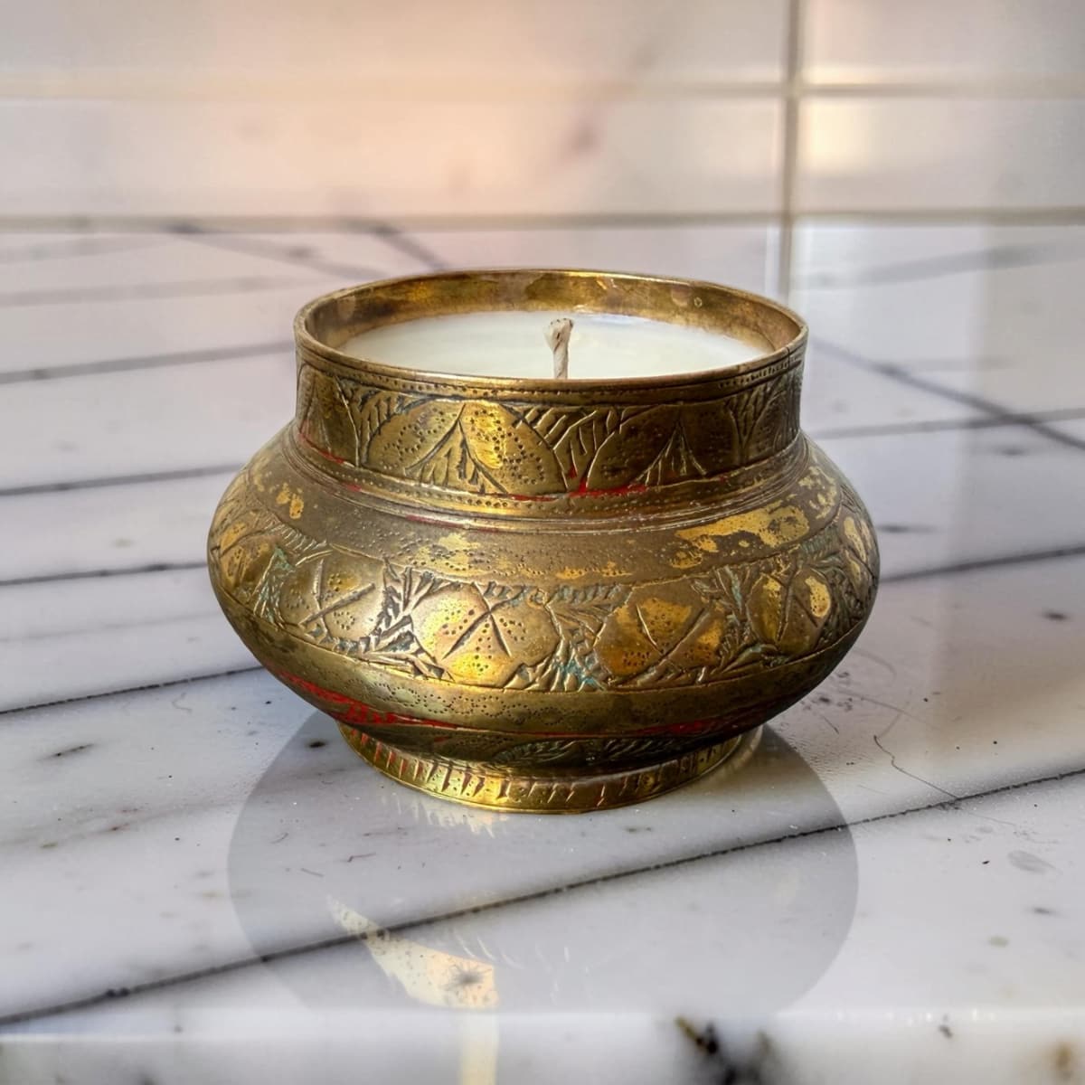 Decorative candle in a brass holder on a marble surface