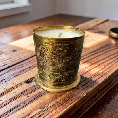 Decorative candle in an ornate brass holder on a wooden surface