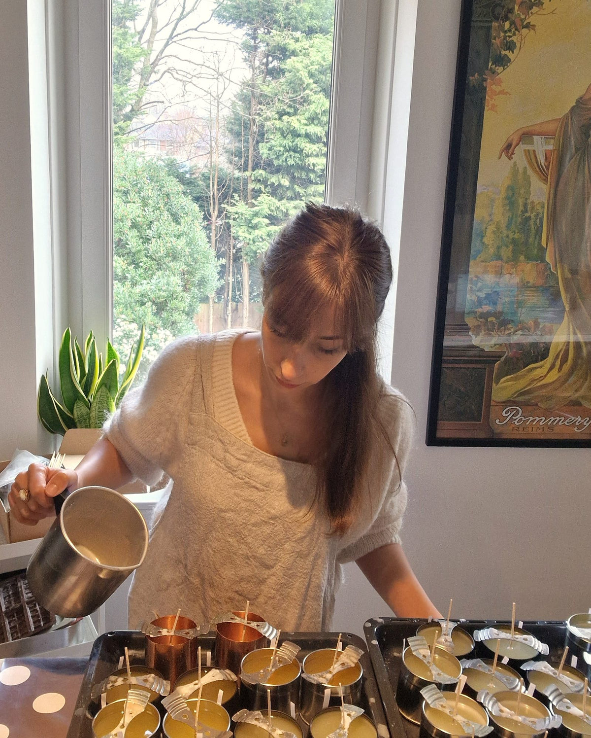 Jo, founder of Ralph's Orchard, hand-pouring natural wax into candle tins and copper vessels