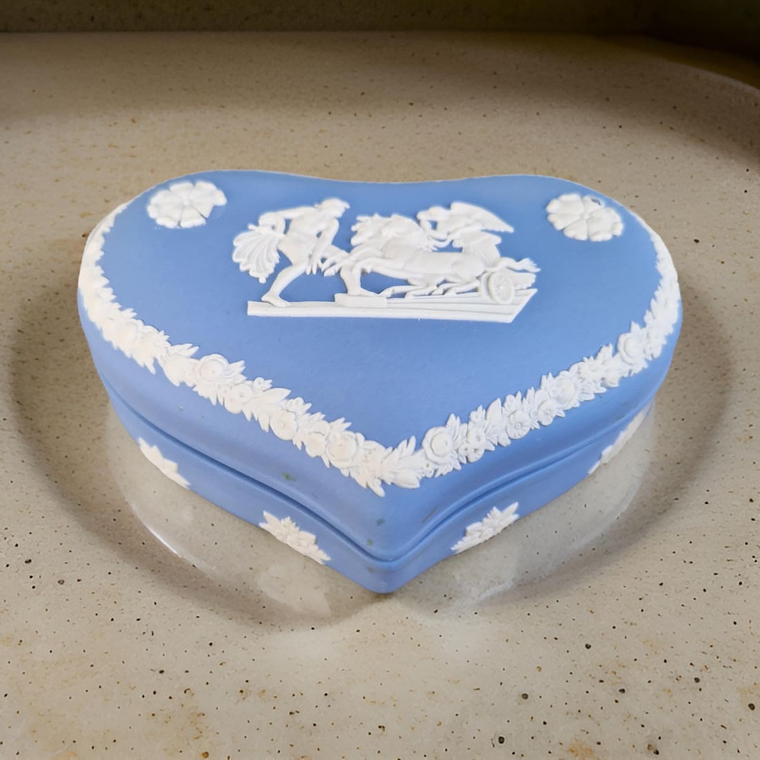 Heart-shaped blue and white decorative box on a beige surface