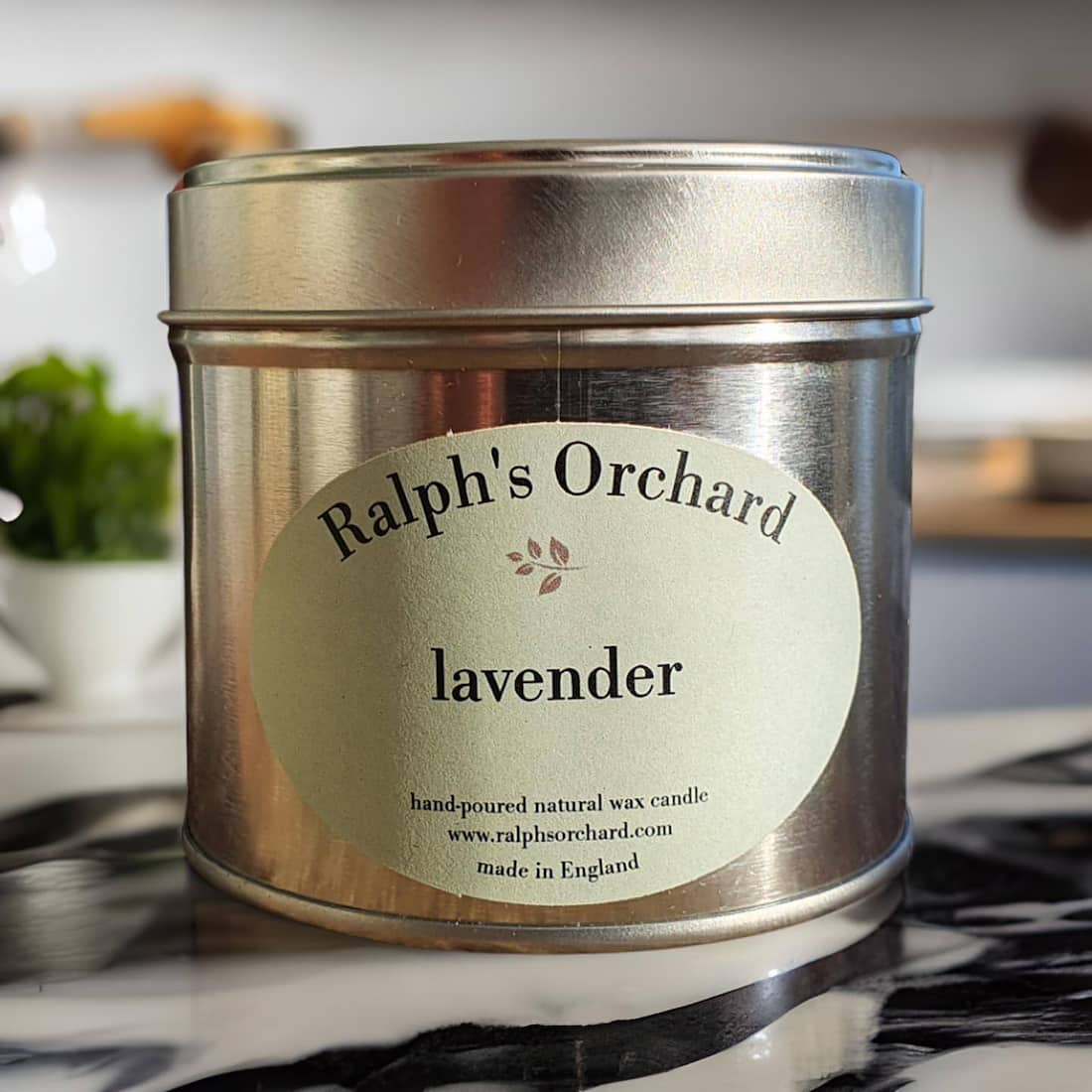 Candle tin labeled 'Ralph's Orchard Lavender' on a marble surface.