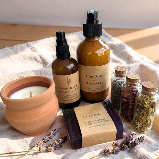 Collection of natural skincare and wellness products including a candle, bottles, and jars on a textured surface.